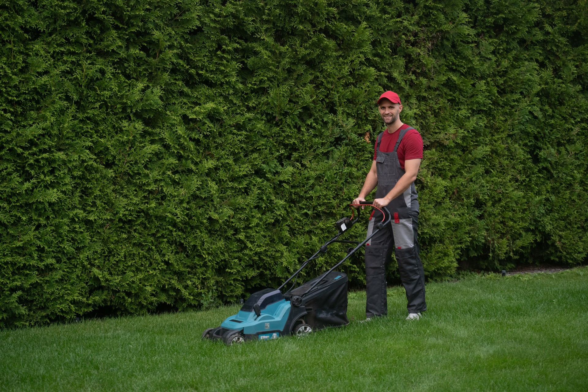Gardener mowing lawn with modern lawnmower